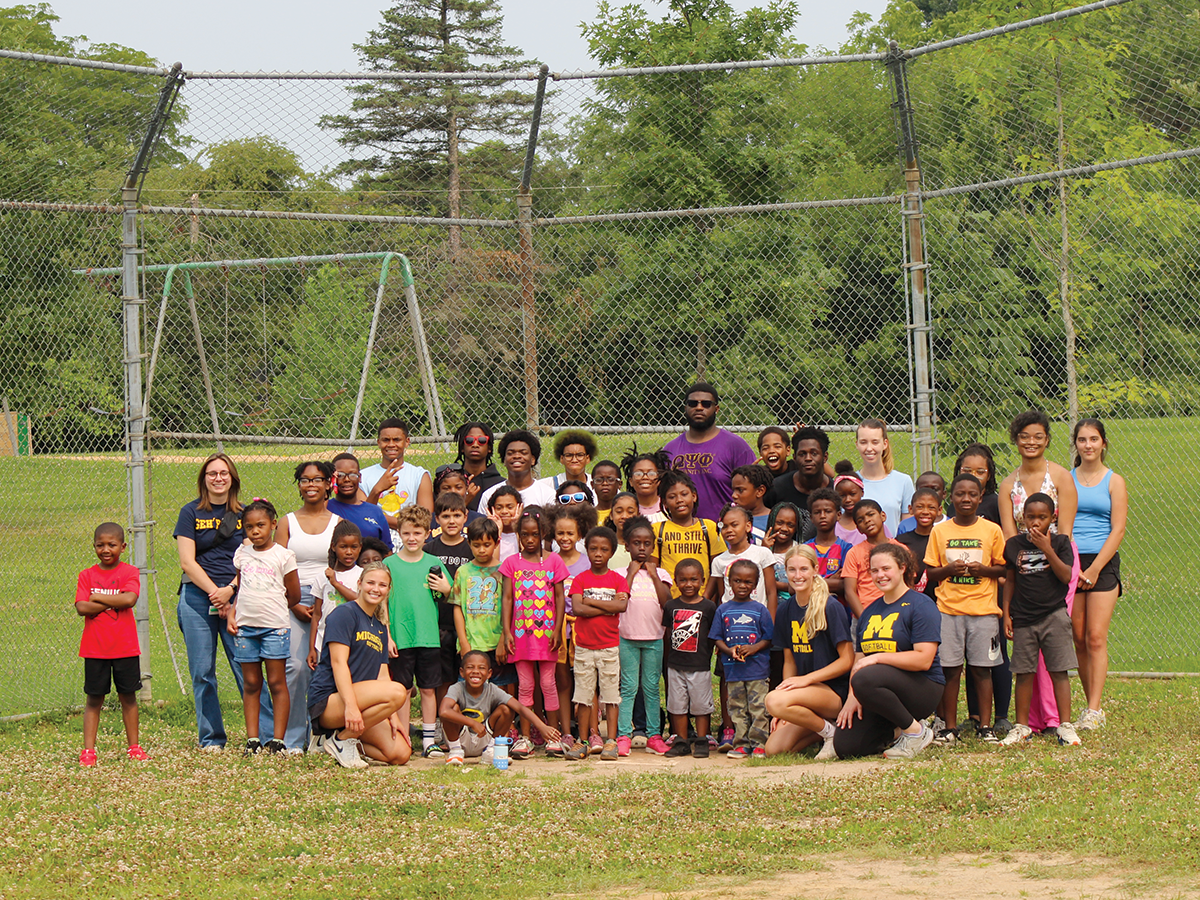 Michigan student-athletes with kids at a Hail! Impact community camp