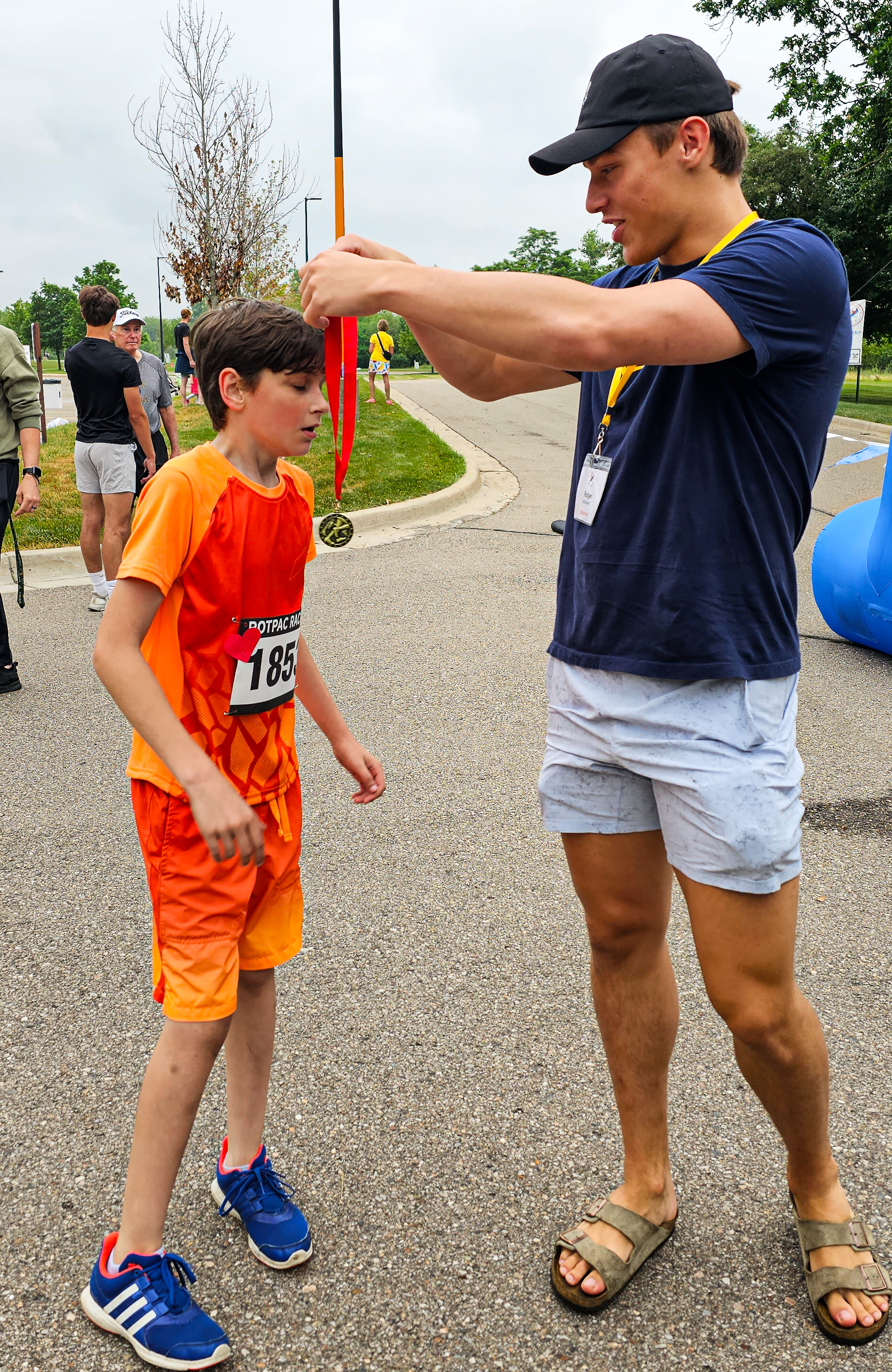 A Michigan student-athlete awarding a young runner his medal